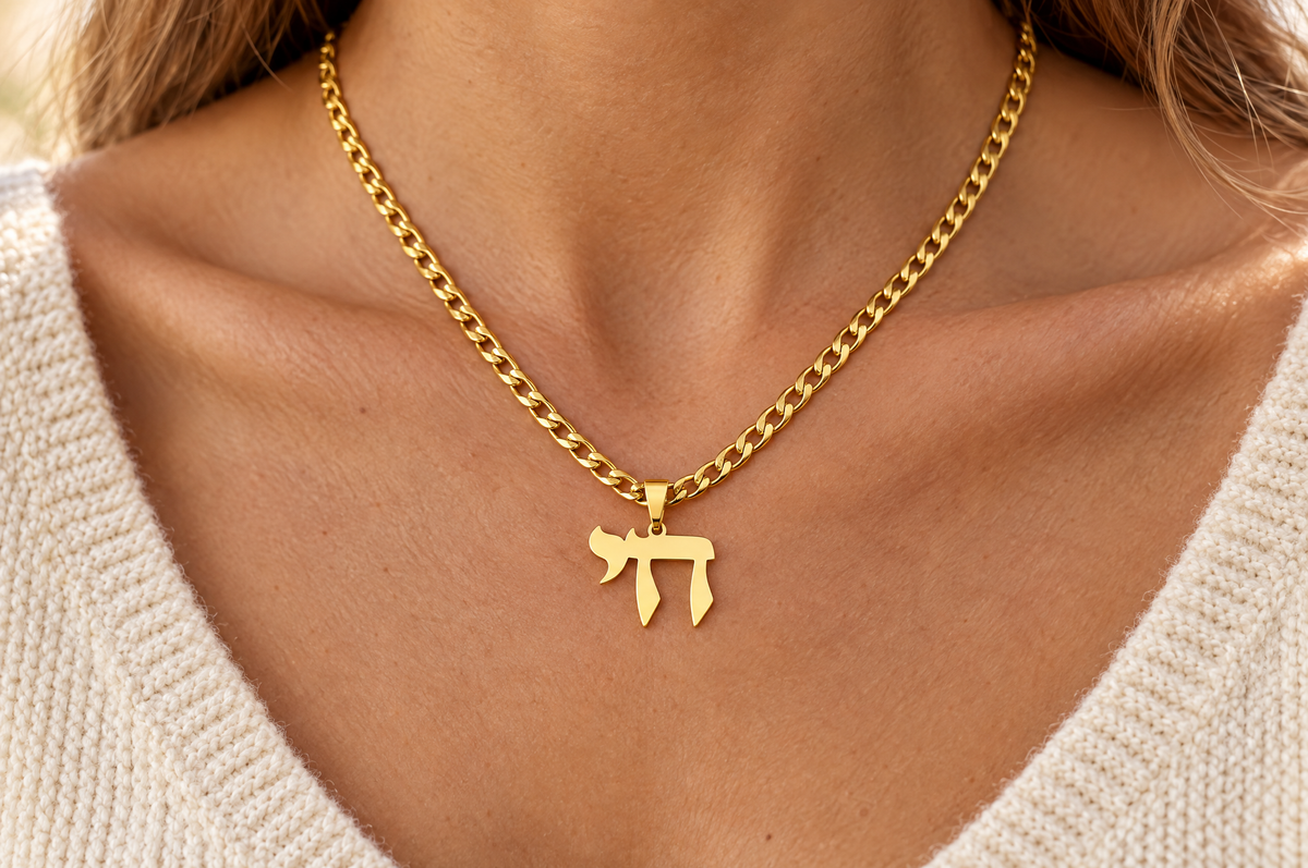 Gold Chai necklace worn over a cream knit top