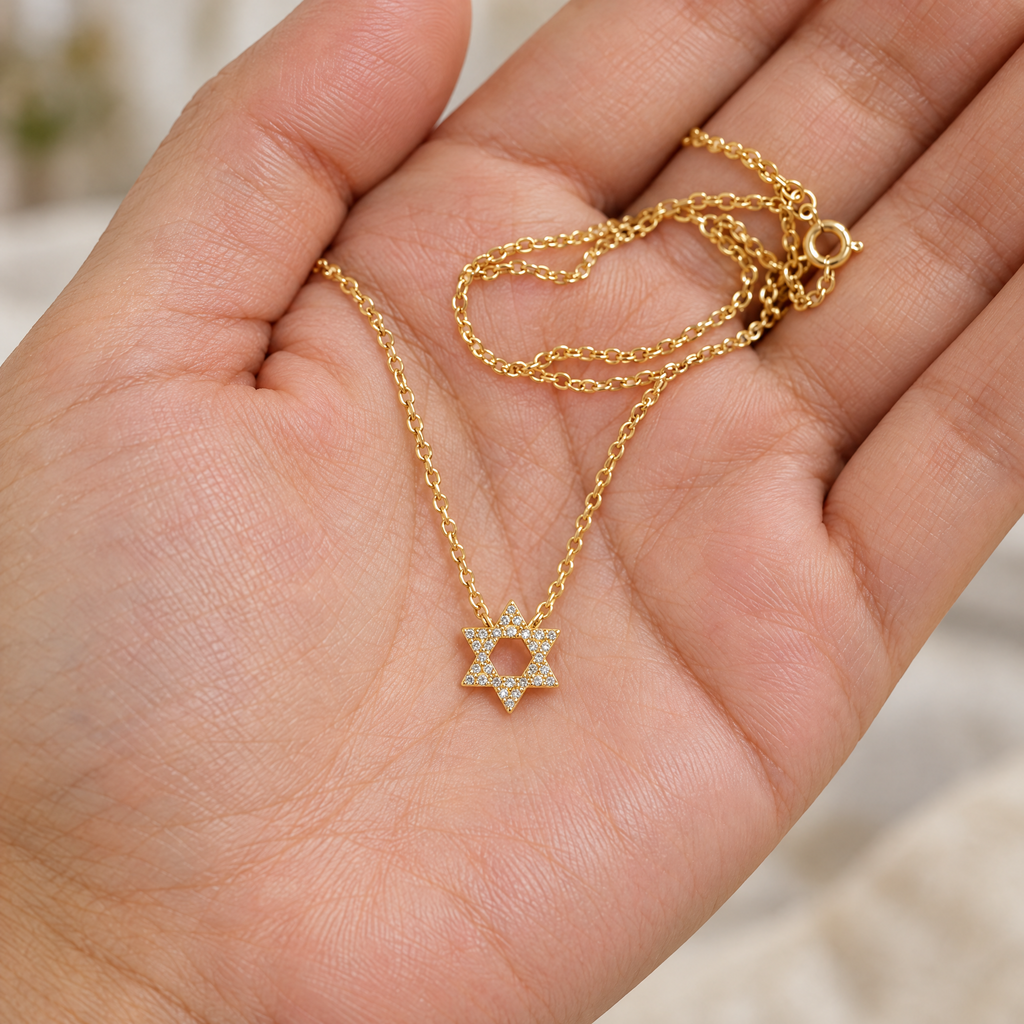 Gold Star of David necklace in the palm of a hand to show its size