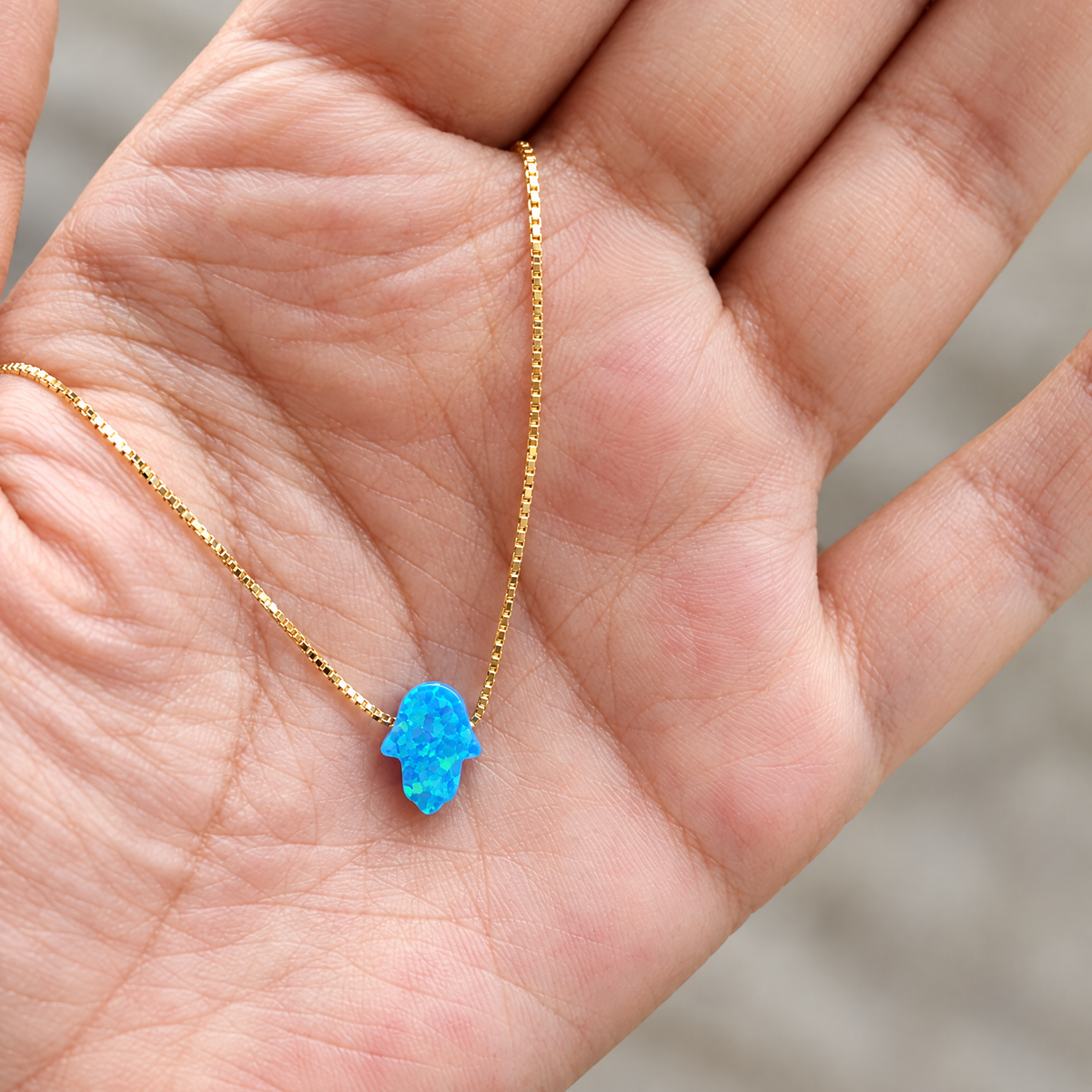 Blue opal hamsa necklace in the hand, to show its real size (8 x 10 mm)