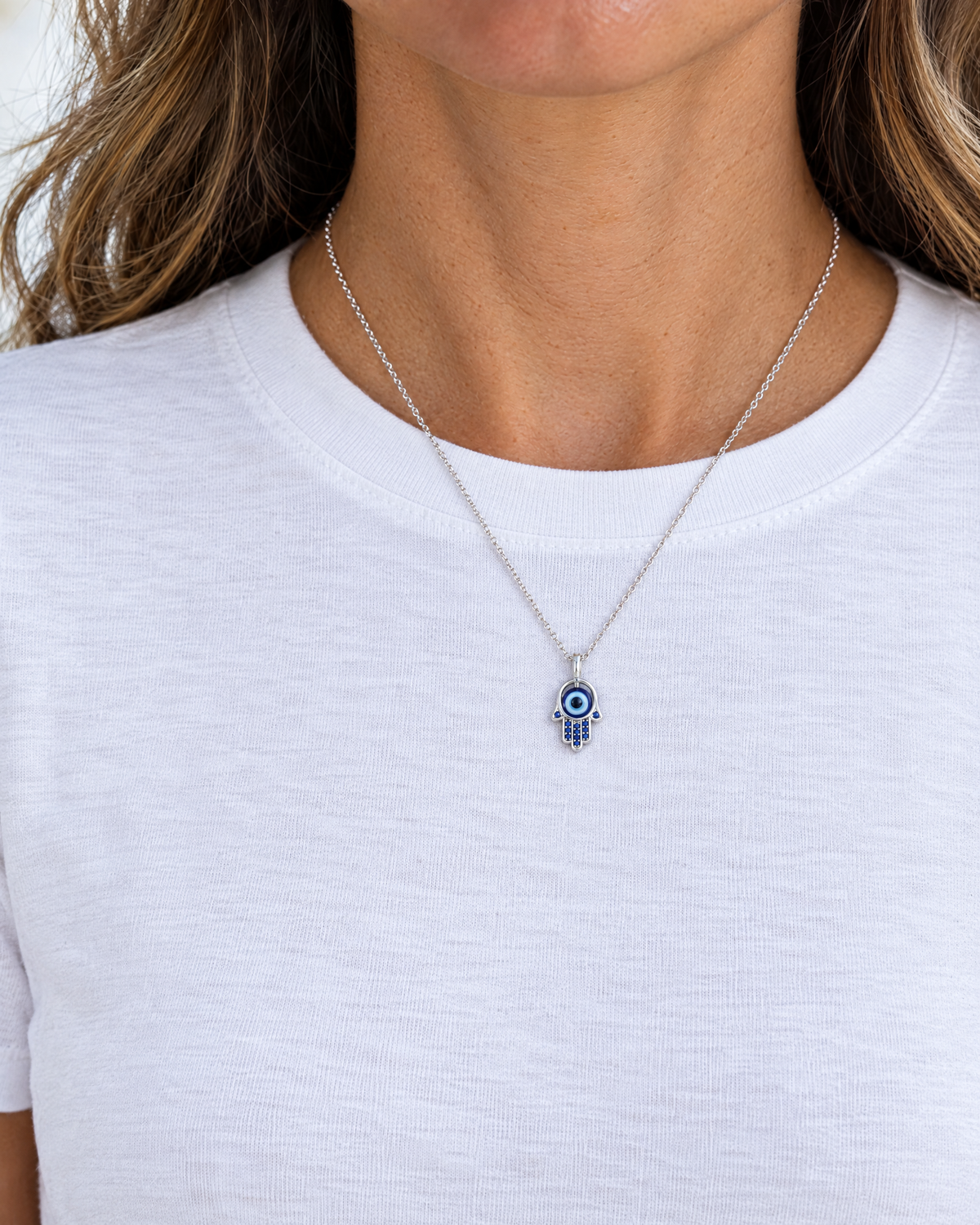 Sterling silver hamsa necklace with blue eye worn, shown at real size (17.5 x 9.8 mm)