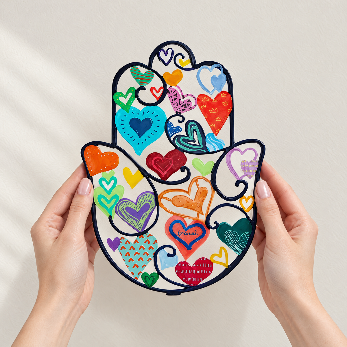 Colorful hamsa wall art held in two hands, to show its real size (18.5 x 25 cm)