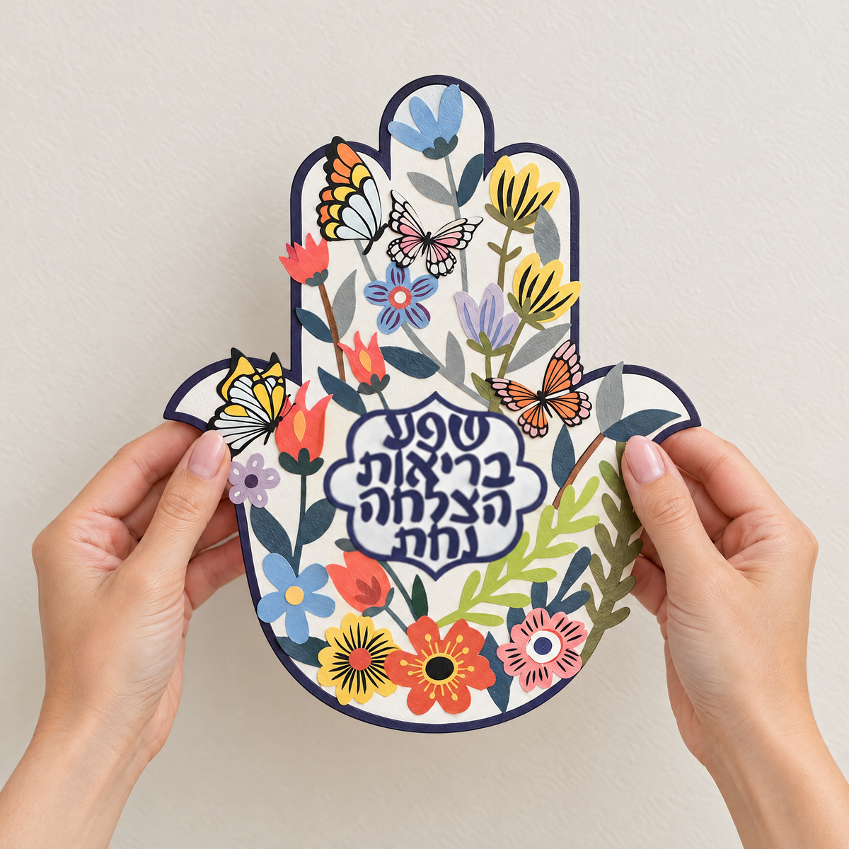 Painted iron hamsa wall art held in two hands, to show its real size (21 x 25 cm)