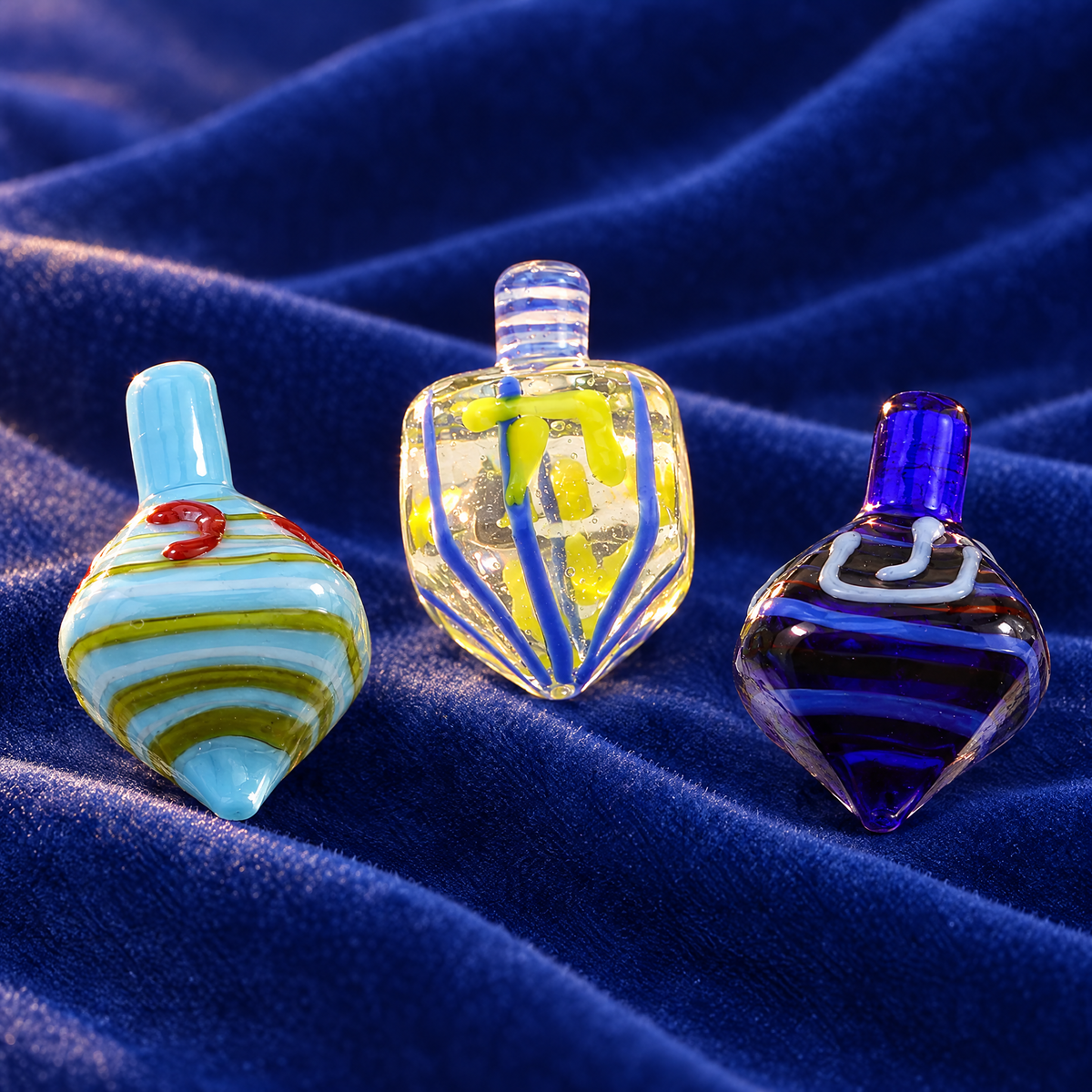 Glass dreidel set of 3 on royal blue velvet