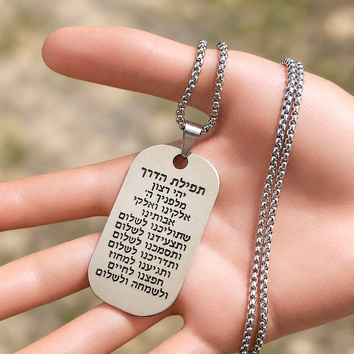 Traveler's Prayer necklace in the hand, to show its real size (50 x 27 mm)